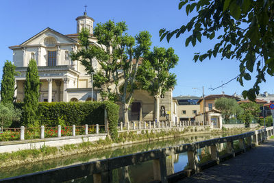 Canal amidst houses and buildings against blue sky