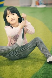 Full length of girl removing socks while sitting on carpet at home