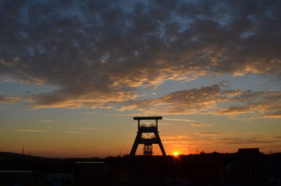 Silhouette tower and buildings against sky during sunset