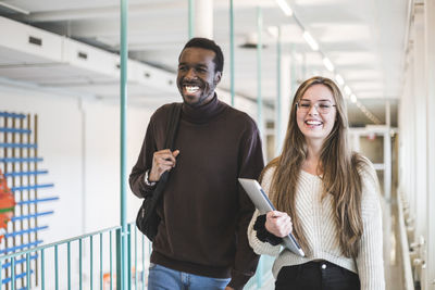 Smiling male and female students walking in corridor of university