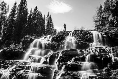 Scenic view of waterfall in forest against sky