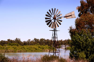 Traditional windmill by lake against sky