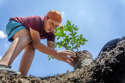 Low angle view of boy doing gardening outdoors