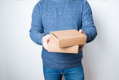 Midsection of man holding box against white background