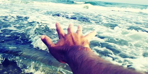 Cropped image of hand on sea shore