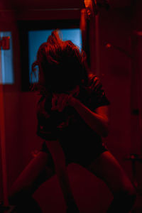 Rear view of young woman sitting at home