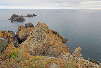 Rock formation on sea shore against sky