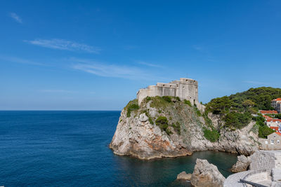 Rock formation by sea against blue sky