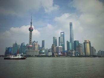 Modern buildings in city against cloudy sky