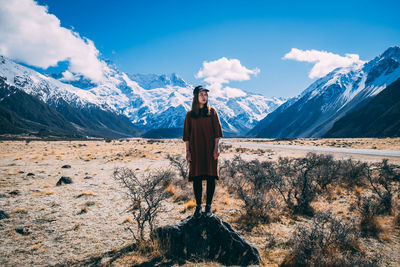 Rear view of person standing on snowcapped mountain against sky