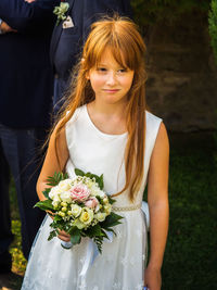 Girl holding bouquet while standing at wedding ceremony