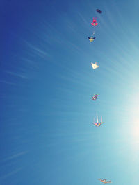 Low angle view of kites flying against blue sky