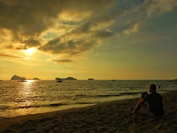 Woman on beach against sky during sunset