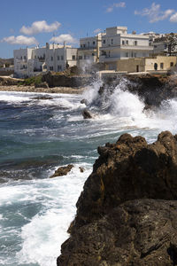 Water flowing through rocks in sea against sky