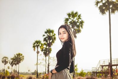 Portrait of beautiful young woman standing against sky