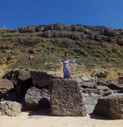 Woman standing on boulder at beach