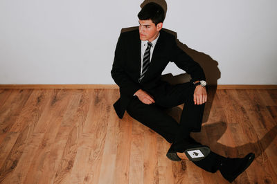 Man with card sitting on floor against wall