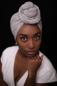 Close-up portrait of beautiful fashion model wearing headscarf against black background