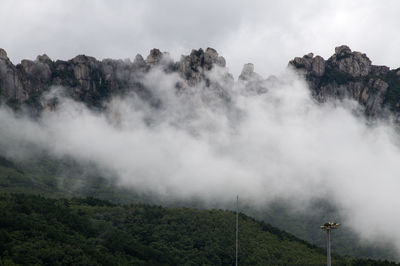 Scenic view of fogged mountain against sky