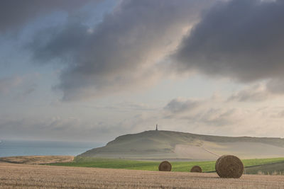 Hay bales on field against sky