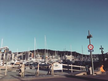 Sailboats moored at harbor against clear blue sky