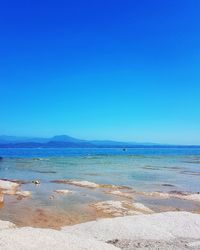 Scenic view of beach against clear blue sky