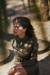 Young woman looking down while sitting on land