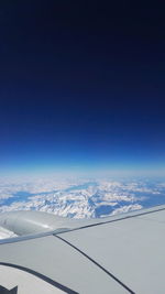 Aerial view of snowcapped mountains against blue sky