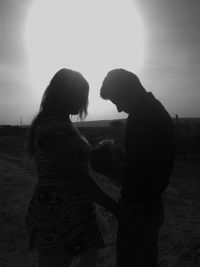 Side view of couple standing on field against sky