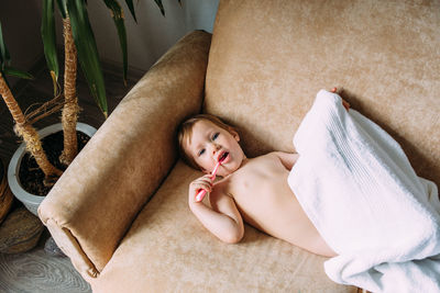 High angle portrait of woman lying on sofa at home