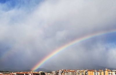 Low angle view of rainbow over city against sky