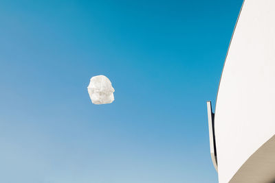 Flying empty white plastic bag in front of modern architecture
