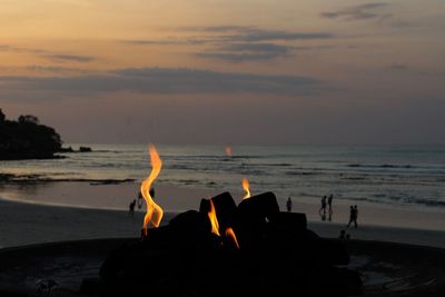 Close-up of silhouette people on beach against sky during sunset