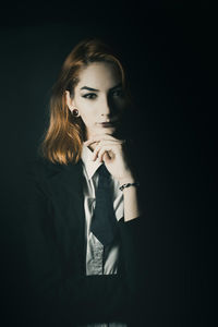 Portrait of young woman against black background