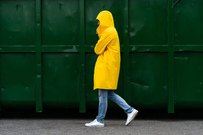 Side view of man wearing raincoat walking on road