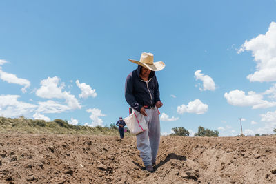 Rear view of woman standing on field against sky