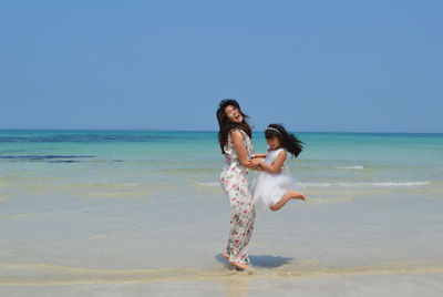 Woman standing at beach against sky