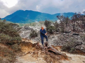 Man standing on rock against sky