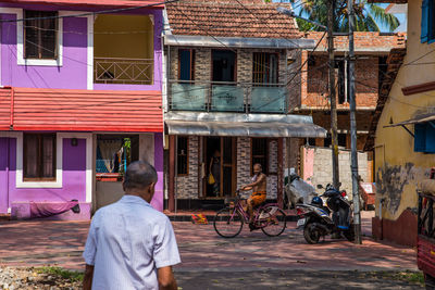 Rear view of man on street against buildings in city