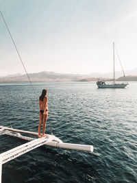 Woman standing on boat over sea against clear sky