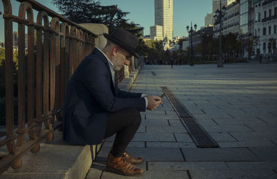 Adult man in suit and hat looking at mobile phone on street. madrid, spain