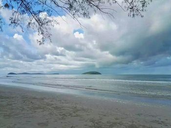 Scenic view of beach against cloudy sky