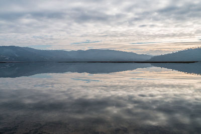 Scenic view of lake by mountains against sky