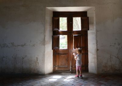 Full length of girl standing against door