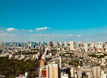 Aerial view of buildings in city against blue sky