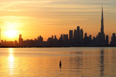 View of sea and buildings against sky during sunset