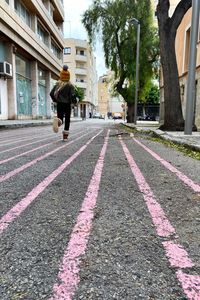 Rear view of man walking on street amidst buildings