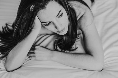 High angle view of thoughtful woman lying down on bed