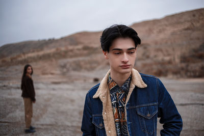 Portrait of young man standing on land against sky