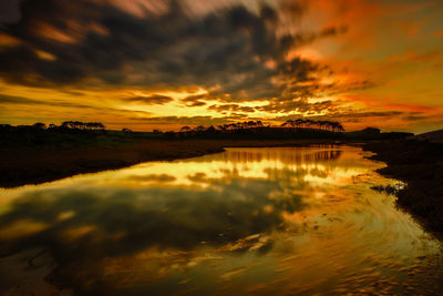 Scenic view of sea against dramatic sky during sunset